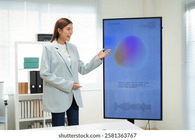 A professional woman presents data on a large screen in a modern workspace, showcasing a colorful graph and engaging with her audience.