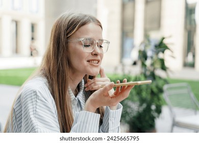 Professional woman using voice assistant on her phone outdoors, enjoying modern technology in an urban setting. - Powered by Shutterstock