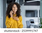 Professional woman in yellow blouse having joyful phone conversation in office, showcasing confidence and happiness. Captures essence of modern communication and business success.