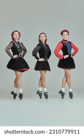 Professional women's Irish dance ensemble in concert costumes and Ghillies Hard Shoes pose together in a row. Full-length studio portrait on a grey background. - Shutterstock ID 2310779911