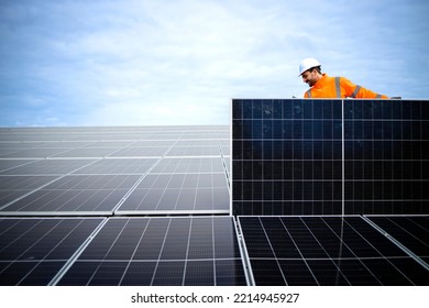 Professional worker in high visibility suit and hardhat carrying photovoltaic panel and installing solar electric plant. - Shutterstock ID 2214945927
