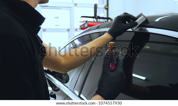 The professional\
worker holds a white sponge in his hand, applies liquid, auto\
repair shop, car washing.