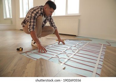 Professional worker installing electric underfloor heating system indoors - Shutterstock ID 1902693556