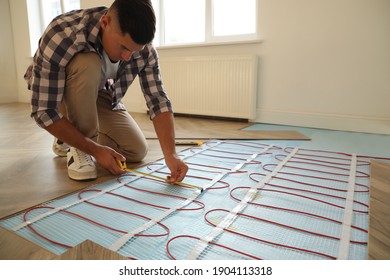 Professional Worker Installing Electric Underfloor Heating System Indoors