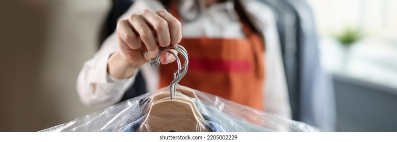 Professional worker keeps clean clothes on hangers - Powered by Shutterstock