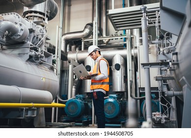 Professional worker of modern factory using laptop controlling program to automatic machinery. Engineering with laptop Programmable Logic Controller to manage large machine working full automatic.