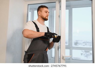 Professional worker in overalls performing window maintenance, adjusting the upvc frame with a screwdriver, ensuring proper installation