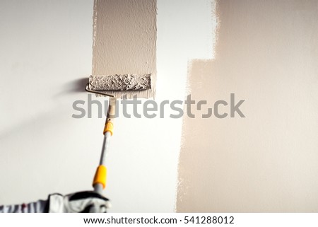 professional worker plastering a wall, painting with paint brush decoration on interior walls