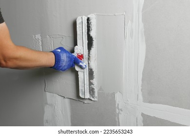 Professional worker plastering wall with putty knife, closeup