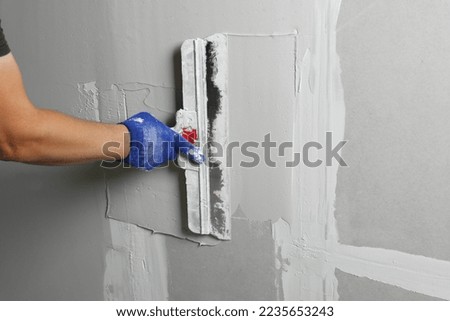 Professional worker plastering wall with putty knife, closeup