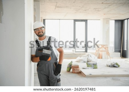 Professional worker plastering wall with putty knife indoors.