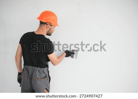 Professional worker plastering wall with putty knife indoors.