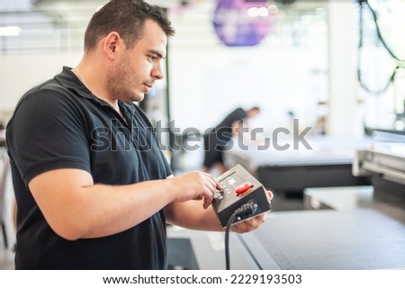 Professional worker printmaker technician operator works in printing press hall and printshop office with many different type of machine