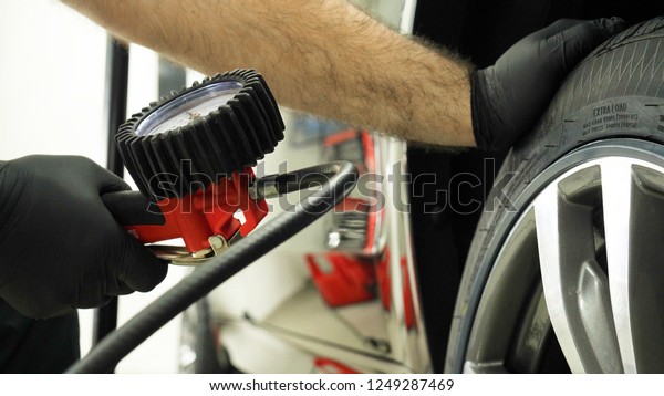 A professional worker in a service\
station checks (pumps) the pressure of the wheels of a car.\
Concepts from: Car, Pressure Sensor, Tech\
Service.