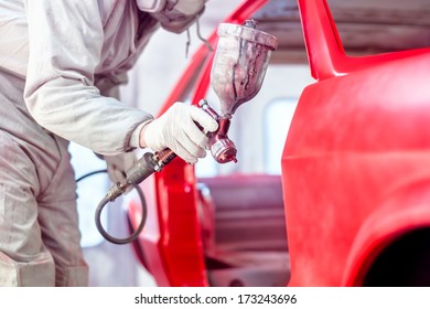 Professional Worker Spraying Red Paint On A Car Body