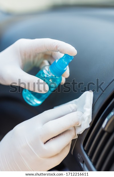 Professional worker using disinfectant and wet\
wipe to clean car\
interior.
