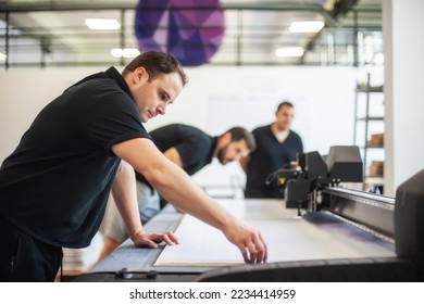 Professional workers graphic technicians operators work in a printing press and print shop with many different types of machines