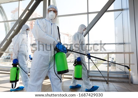 Professional workers in hazmat suits disinfecting indoor accommodation, pandemic health risk, coronavirus