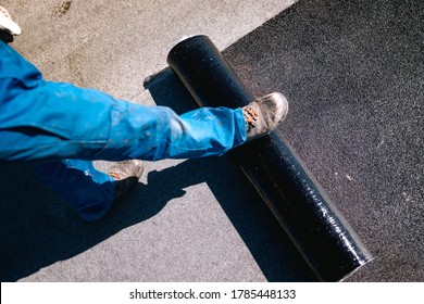 Professional Workers Insulating Rooftop With Bitumen Membrane. Waterproofing Details At Construction Site