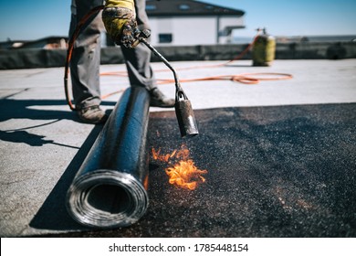 Professional workers insulating rooftop with bitumen membrane. Waterproofing details at construction site. Bituminous membrane waterproofing system details and installation on flat rooftop. - Shutterstock ID 1785448154