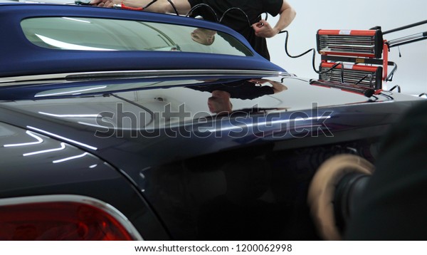Professional\
workers polish the car and put ceramics in the garage. Concept:\
auto shop, coverage, service, car\
wash.
