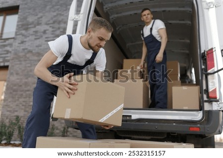 Professional workers stack carton boxes for transportation. Concept of trade transit on truck or carriage van. Job of delivery man on piling packs at lorry for dispatch. Modern international shipment