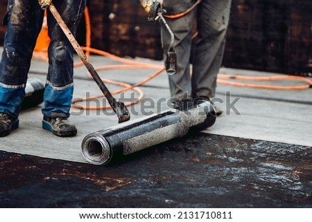 Professional workers waterproofing house construction site. Worker rolling membrane