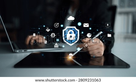 Professional working on digital security using tablet and laptop, showcasing technology, data protection, and online safety symbols in a modern workspace Quark.