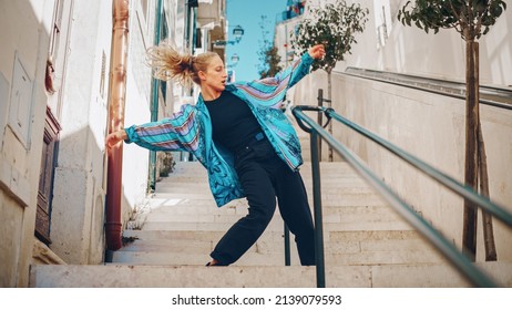 Professional Young Adult Woman in Casual Stylish Clothes Actively Breakdancing Hip Hop on the Street of an Old Town in a City. Scene Shot in an Urban Environment on an Quiet Small Town Stairs. - Powered by Shutterstock