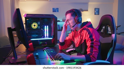 Professional Young Asian Male Gamer Playing Online On His PC In The Living Room At Night - He Upset Because Of Losing The Game