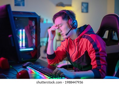 Professional Young Asian Male Gamer Playing Online On His PC In The Living Room At Night - He Upset Because Of Losing The Game