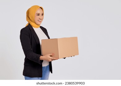 Professional young Asian Muslim businesswoman wearing a black suit standing looking aside with holding a package box and delivery for shopping online via e-commerce  isolated on white background - Powered by Shutterstock