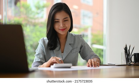 Professional Young Businesswoman Using Calculator And Preparing Annual Financial Report At Office Desk