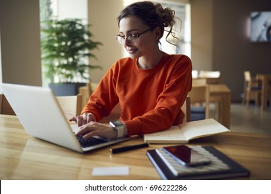 Professional young copywriter in trendy eyewear working on creation advertising content typing on laptop computer connected to wireless internet, skilled journalist browsing information in web site - Powered by Shutterstock