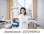 Professional young dentist posing beside modern equipment in a dental clinic.