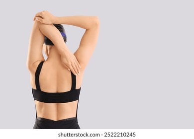 Professional young female swimmer stretching on grey background, back view - Powered by Shutterstock