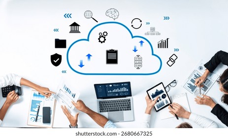 Professionals collaborate around a table using digital devices, discussing cloud technology while analyzing data through charts and graphs in a modern workspace. Trope