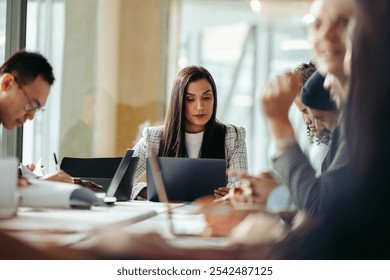 Professionals collaborating in a business meeting, emphasizing teamwork, communication, and focus in a modern office environment. - Powered by Shutterstock