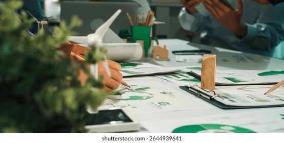 Professionals in a collaborative workspace focus on sustainable development projects. Green technology and eco-friendly materials enhance team brainstorming and productivity. SACTR