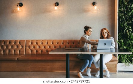 Professionals in a coworking space collaborate and discuss ideas. Businesswomen and coworkers work on laptops, engaging in discussions. They emphasize teamwork, analyze data, and develop software. - Powered by Shutterstock