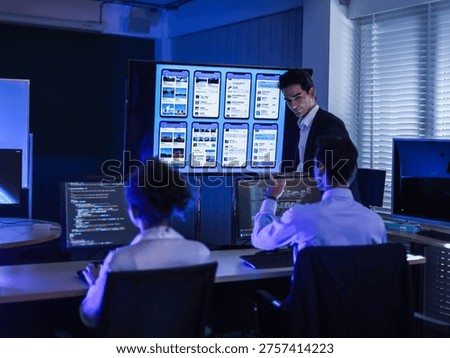 IT professionals developing mobile app UI UX design on large screen in dark office. Software engineers coding and analyzing user interface wireframes for digital product development at night