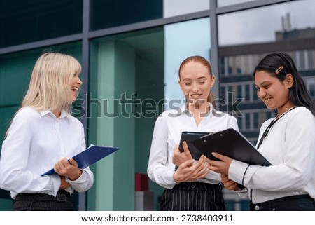 Professionals discuss work documents outside a modern office building in a city setting