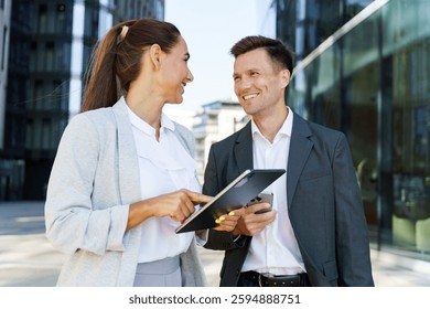 Professionals discussing ideas while standing outside a modern office building during the day