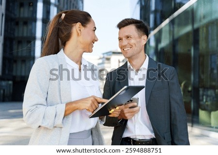 Professionals discussing ideas while standing outside a modern office building during the day