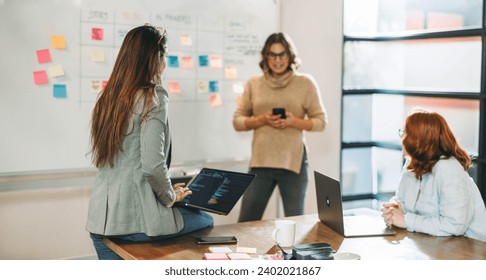 Professionals from diverse backgrounds engage in a creative discussion. With smiles and enthusiasm, a young, multicultural team of entrepreneurs brainstorm and collaborate on a project in a boardroom. - Powered by Shutterstock