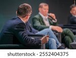 Professionals engage in a panel discussion at business conference. Focused conversation emphasizes collaboration and insights within industry context.