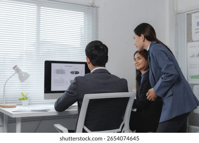 Professionals in a modern office analyzing data on a computer screen, engaging in collaborative discussion and teamwork for a project