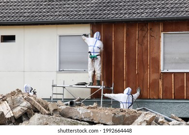 Les professionnels en costumes de protection enlèvent l'amiante sur un mur