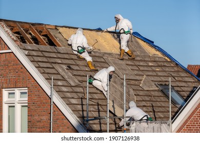 Professionals in protective suits remove asbestos-cement roofing underlayment - Shutterstock ID 1907126938