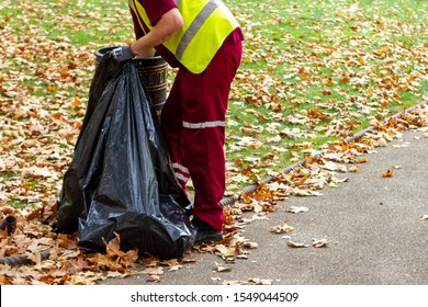 Professionell litter picker or dust bin man picking up rubbish from a dust bin in a park in Camden, London